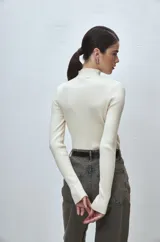 Polera de punto color crema, con cuello alto y mangas largas.