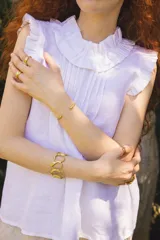 Blusa de lino color blanco, sin mangas, con cuello fruncido y volados de encaje en las sisas. Presenta pinzas frontales y un diseño de calce holgado de estilo romántico.