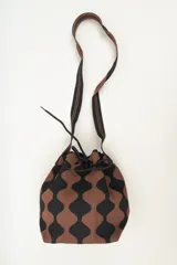 Bolso tipo bombonera tejido a crochet, con patrón geométrico en tonos rosa y marrón. Tiene cierre con cordón ajustable y correa de hombro.