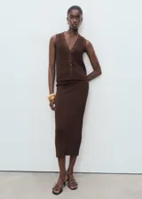 Chaleco de punto fino color marrón, con cuello de pico y cierre frontal con botones. Presenta un diseño recto sin mangas con tirantes anchos.