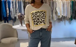 Sweater manga larga color crudo con escote en pico y estampado de leopardo en el frente con marco dorado.