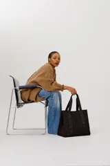 Bolso tote negro con asas de cinta con el logo de la marca en color gris.