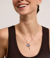Collar dorado con cadena fina y dijes colgantes: perla barroca artificial, palito de metal y resina redondeada con strass.