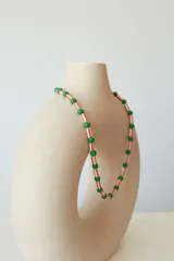 Collar corto tipo choker de cuentas plásticas amarillas y tubos de plástico verde.