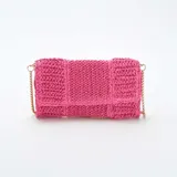Bolso de mano tipo clutch color fucsia, tejido en rafia, con solapa y cadena dorada para usar como bandolera.