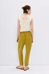 Pantalón babucha de tiro alto confeccionado en símil lino color verde oliva. Tiene calce relajado que ajusta hacia el ruedo y largo hasta los tobillos, la cintura es elastizada y cuenta con 6 presillas y lazo de ajuste en la misma tela. Tiene bolsillos diagonales en laterales y dos bolsillos ojal falsos en espalda.