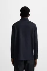 Camisa blanca de corte regular, cuello italiano, manga larga con puños abotonados y cierre frontal con botones.