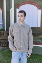 Campera de denim color beige, con cuello amplio, puños con botones y cierre frontal con botones. Incluye bolsillos en el pecho y laterales. Tejido denim de sarga resistente y con protección contra el viento.