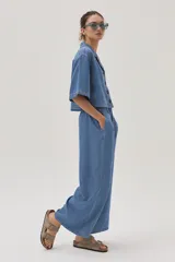 Blusa celeste de denim con cuello camisero, mangas cortas y cierre frontal con botones.