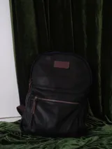 Mochila de cuero color marrón con forro de lino y cierres de bronce. Tiene un compartimento interno acolchado para computadora portátil.
