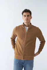 Campera marrón de algodón con cierre frontal, cuello alto, bolsillos laterales, puños y logo bordado en el pecho.