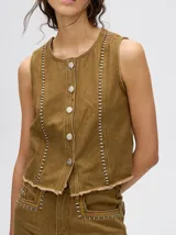 Chaleco corto de denim negro con apliques metálicos y flecos en el ruedo.