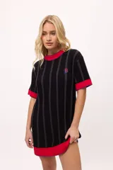 Vestido corto negro con rayas verticales grises, cuello redondo y mangas cortas con ribete rojo.