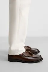 Mocasín de vestir color marrón oscuro, con detalle de borlas en la parte delantera.