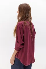 Camisa negra de manga larga con cuello clásico y cierre frontal con botones. Presenta costuras decorativas en color blanco.