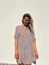 Camisero corto color habano con bordado de líneas verticales blancas. Tiene cuello camisero, mangas cortas y cierre frontal con botones.