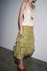 Falda midi color verde oliva confeccionada en tejido con viscosa. Presenta cintura elástica y detalle de volantes en el mismo tejido.