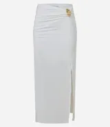 Conjunto de dos piezas color blanco, compuesto por un top tipo corset strapless con escote en V y una pollera midi ajustada con fruncido lateral y abertura alta, asegurada con un adorno metálico.