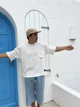 Remera blanca de corte cuadrado con bolsillo en el pecho y logo estampado en negro.