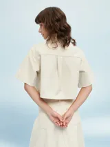 Camisa de manga corta color celeste, con cuello clásico, cierre frontal con botones y bolsillo de parche en el pecho.