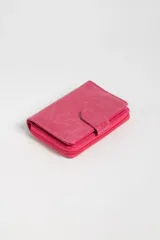 Billetera pequeña fucsia con textura símil cocodrilo, cierre con broche a presión y compartimento con cierre de cremallera.
