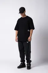 Remera negra oversize de algodón con cuello redondo y mangas cortas. Estampado pequeño en el frente y estampado grande en la espalda con la frase "Curbside Treasure".