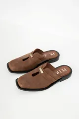 Zuecos con estampado animal print en blanco y negro, con tira ancha de cuero negro y aplique metálico.