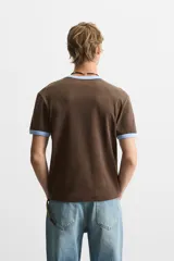 Camiseta azul marino de corte regular, cuello redondo y manga corta con ribete blanco en cuello y mangas.
