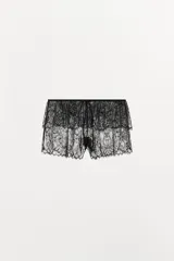 Short de encaje negro semitransparente, de tiro medio, con cintura elástica ajustable con lazada, detalle de volantes y bajo con acabado en ondas.