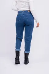 Pantalón de jean azul oscuro, corte mom, tiro alto y ruedo arremangado.