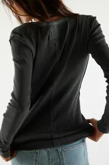 Camiseta tipo henley de manga larga, color blanco, confeccionada en algodón elástico con cuello redondo y tapeta de botones.