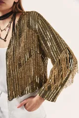 Saco corto con lentejuelas doradas y flecos.
