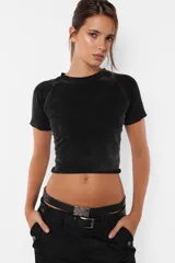 Remera corta negra con efecto gastado, mangas cortas raglán y cuello redondo con terminaciones al corte.