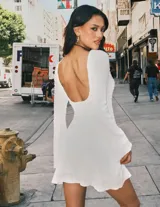 Minivestido blanco de manga larga acampanada, con cinturón marrón de cuero con apliques metálicos.