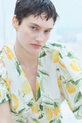 Blusa corta con escote en V pronunciado, elásticos finos en la cintura y peplum. Mangas globo cortas con elástico oculto en los puños. Estampado de limones y hojas verdes.