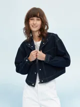 Campera corta de jean azul oscuro con costuras en hilo color crema, cuello mao y cierre con botones metálicos.