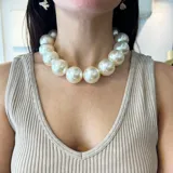 Collar de perlas grandes color blanco, con cierre de mosquetón de metal dorado y cadena para regular el largo.