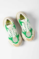 Zapatillas deportivas de malla blanca con superposiciones de cuero color beige y verde. Suela gruesa de goma color hueso.