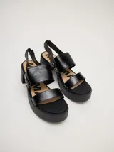 Sandalias negras de cuero con plataforma y taco ancho. Tienen correa trasera con elástico y doble argolla en la parte externa e interna.