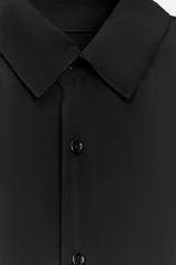 Camisa negra fluida confeccionada en hilatura con cupro, de cuello solapa y manga larga acabada en puño. Cierre frontal con botones.