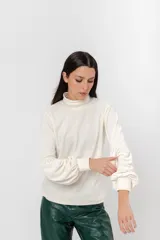 Polera de plush color blanco con cuello alto y mangas largas abullonadas.