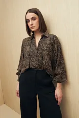 Camisa marrón con estampado animal print negro, de calce relajado, cuello clásico, abotonadura frontal y mangas largas con puños camiseros.