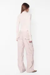 Body manga larga color beige, de punto roma, con cuello medio alto con cierre de nylon a tono. Tiene recortes pisados con bordador, mangas ranglan con mitones en los puños, broches snap en la entrepierna y elástico interno en el contorno de tiro.