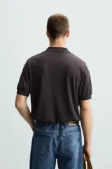 Polo negro de punto tejido en hilatura con algodón y lyocell, corte regular fit, cuello solapa con cierre frontal de botonadura, manga corta y acabados en rib.