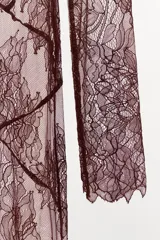 Vestido midi semitransparente de encaje floral color borgoña, con cuello barco, mangas largas y espalda con escote en V. Presenta costuras marcadas y terminaciones onduladas.