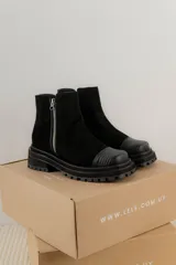 Bota corta de cuero gamuzado color marrón chocolate, con punta cuadrada y suela track. Presenta una correa con hebilla desmontable y cierre lateral con cremallera.