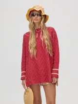 Sweater color crema con tejido en ochos, cuello redondo, puños acanalados con doble raya azul y tajos a los costados.
