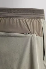 Shorts de entrenamiento color verde oliva, confeccionado en tejido técnico ligero y elástico con perforaciones. Tiene forro interior, cintura elástica ajustable con cordón, bolsillos laterales, bolsillo trasero con cierre de cremallera, bajo con aberturas laterales y logo estampado en la pierna.