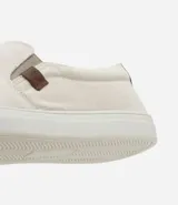 Championes slip on color crudo, con elásticos laterales y detalle de etiqueta marrón con logo en el lateral.