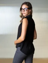 Blusa negra de gasa marca Tahari, con cuello a la base con solapa, abertura central con botones ocultos y detalle plisado en hombros.